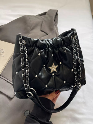 Black quilted shoulder bag with rhinestone star and diamond pattern details.