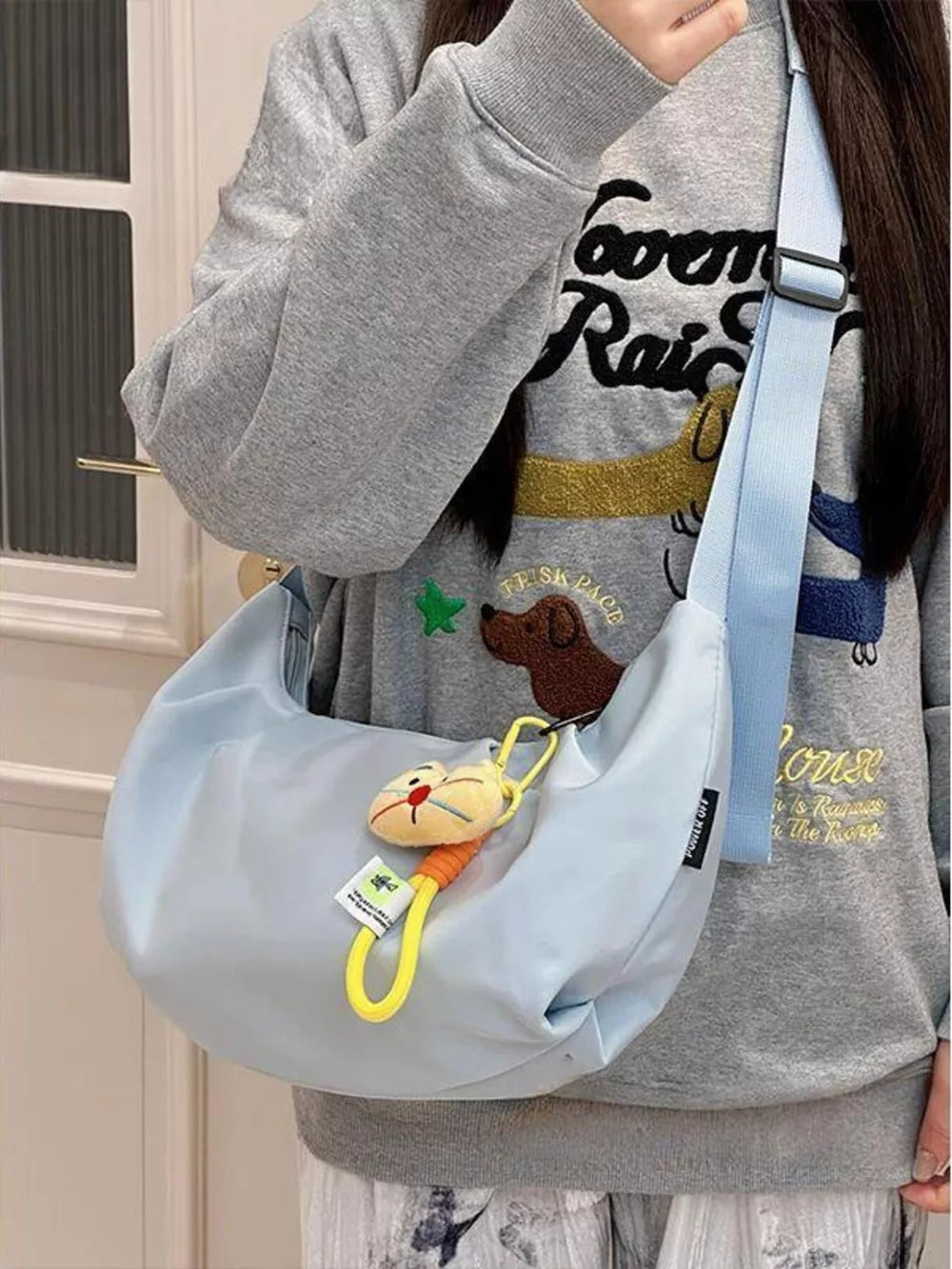 Light blue crescent crossbody bag with adjustable strap and cat charm