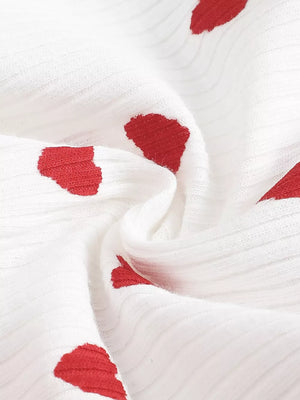White ribbed cotton baby dress with red heart pattern and frill detail.
