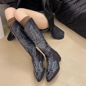 Black knee-high boots with pointed toes and blue embroidery.