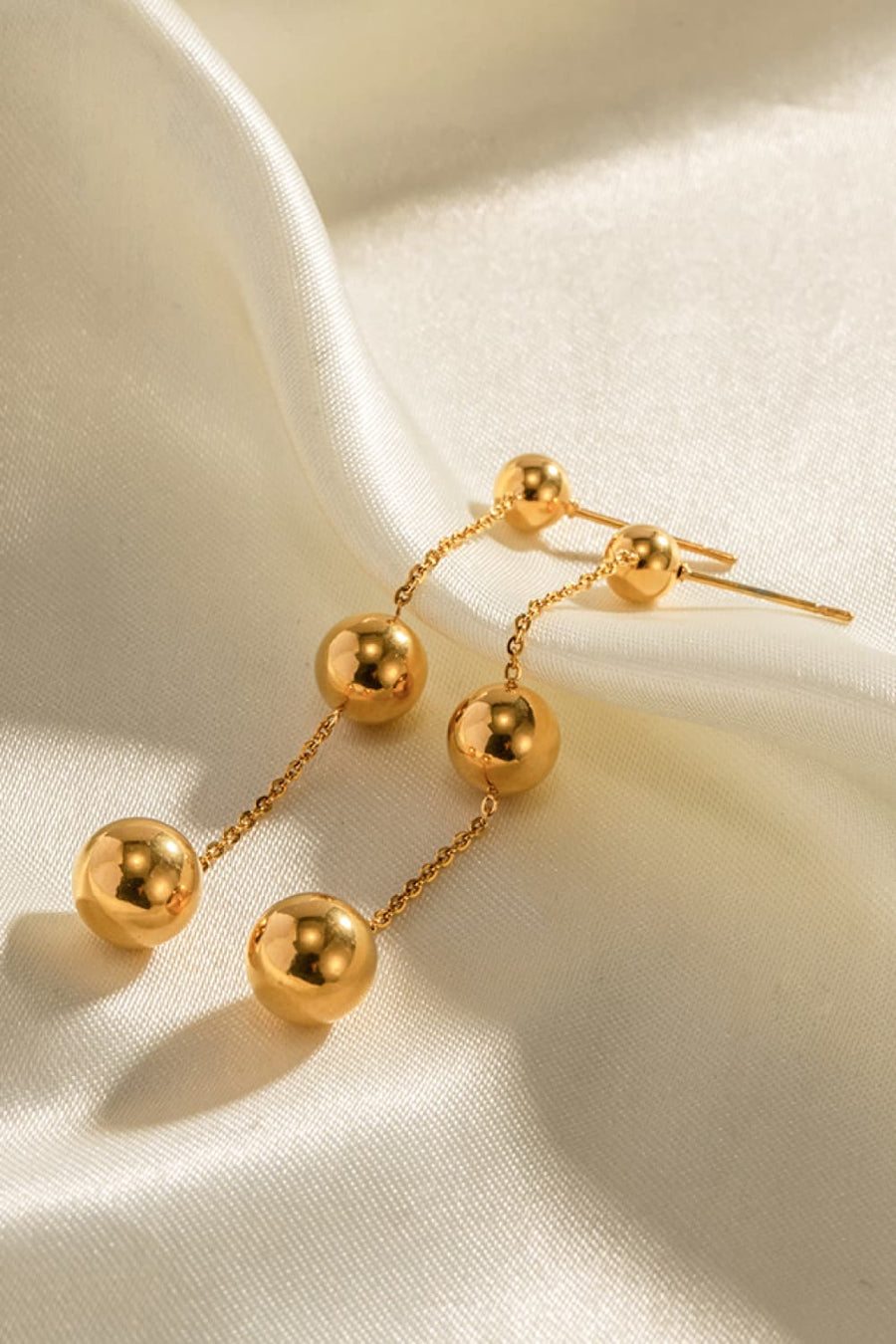 Gold triple orb drop earrings with delicate chain detail.