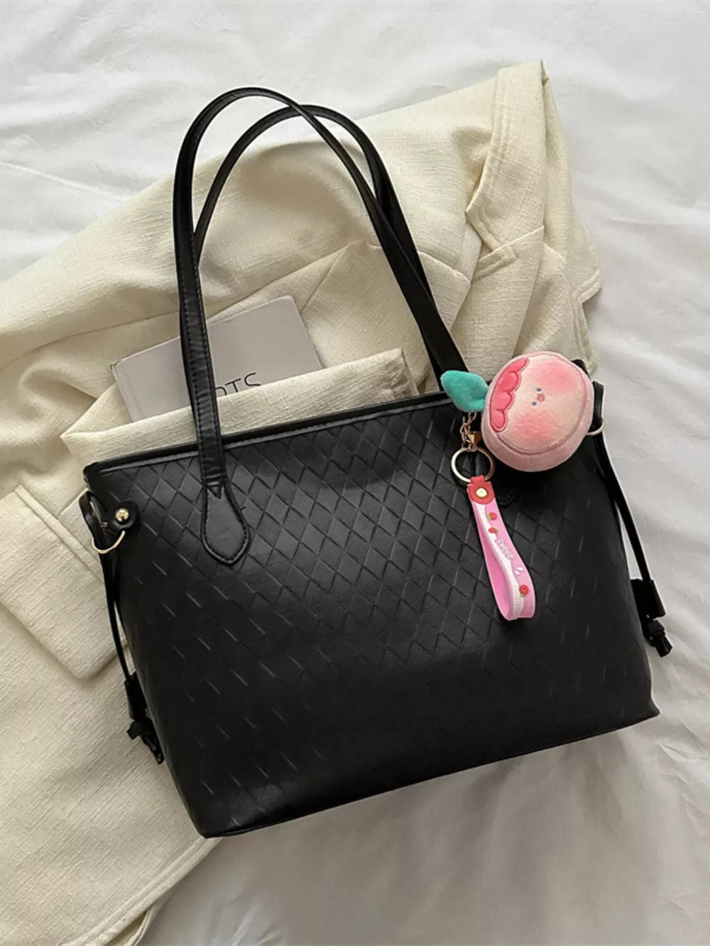 Black textured diamond woven tote bag with a cute fruit charm and pink strap.