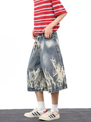 Men's wide-leg denim shorts with abstract bleach pattern and pockets.