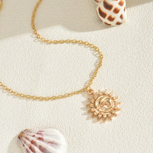 Gold sunburst pendant necklace with celestial face detail on a delicate chain.