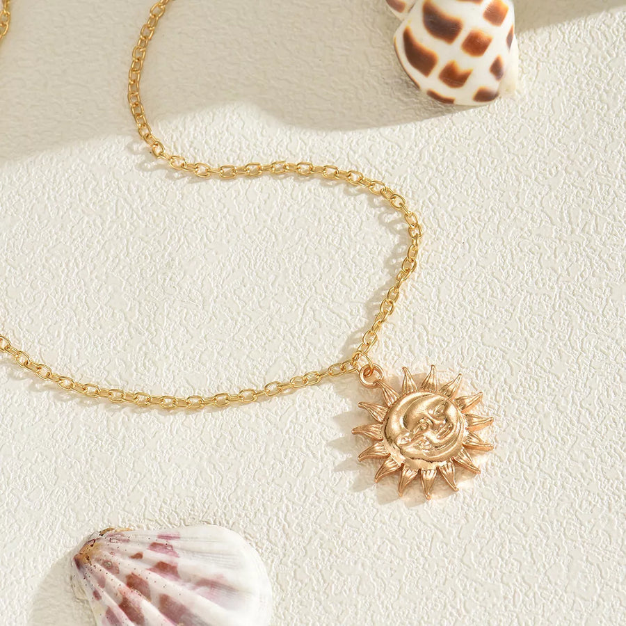 Gold sunburst pendant necklace with celestial face detail on a delicate chain.