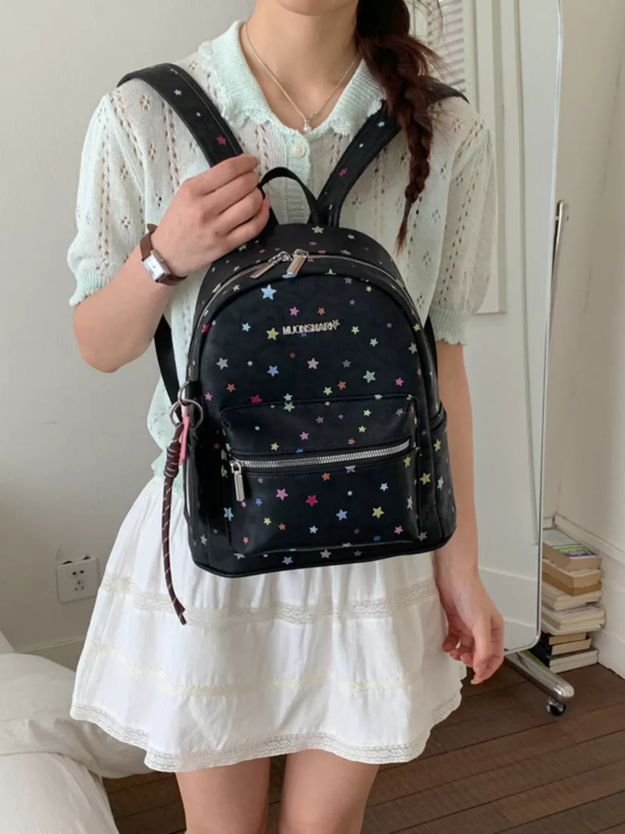 Black mini backpack with colorful star pattern and front zipper pocket.