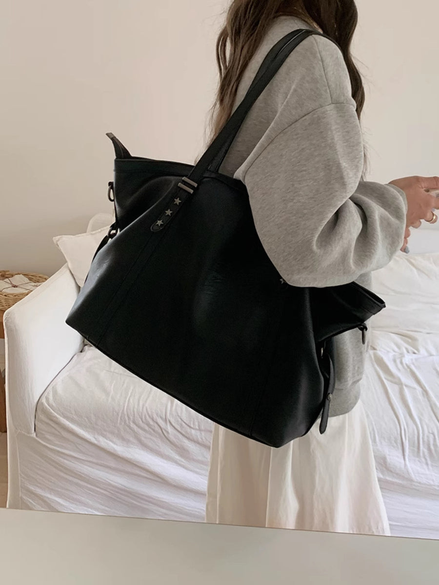 Black pu leather crossbody bag with star details and adjustable strap.