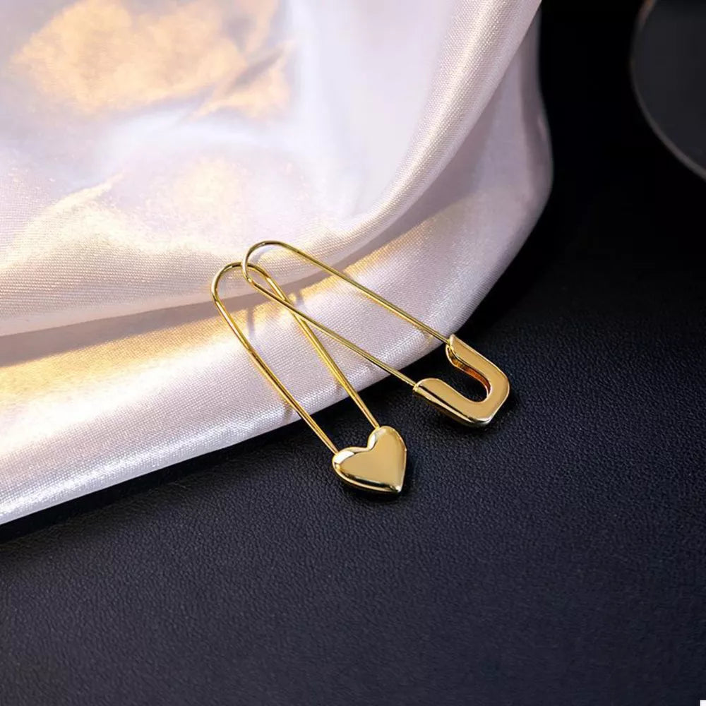 earrings in gold featuring heart charm and elongated fit