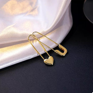 earrings in gold featuring heart charm and elongated fit