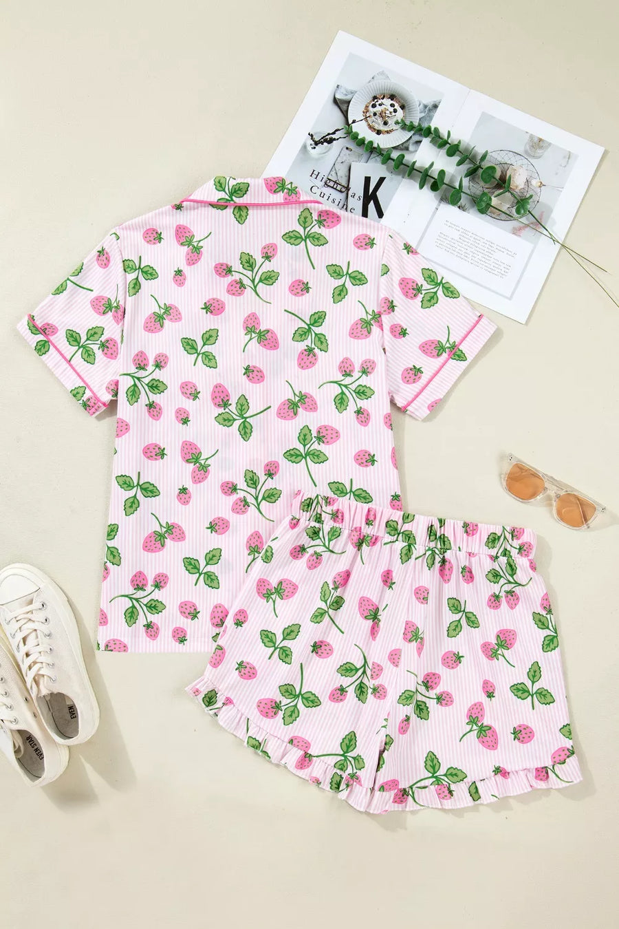 Pink striped pajama set with a strawberry print, featuring a button-up top and ruffled shorts.