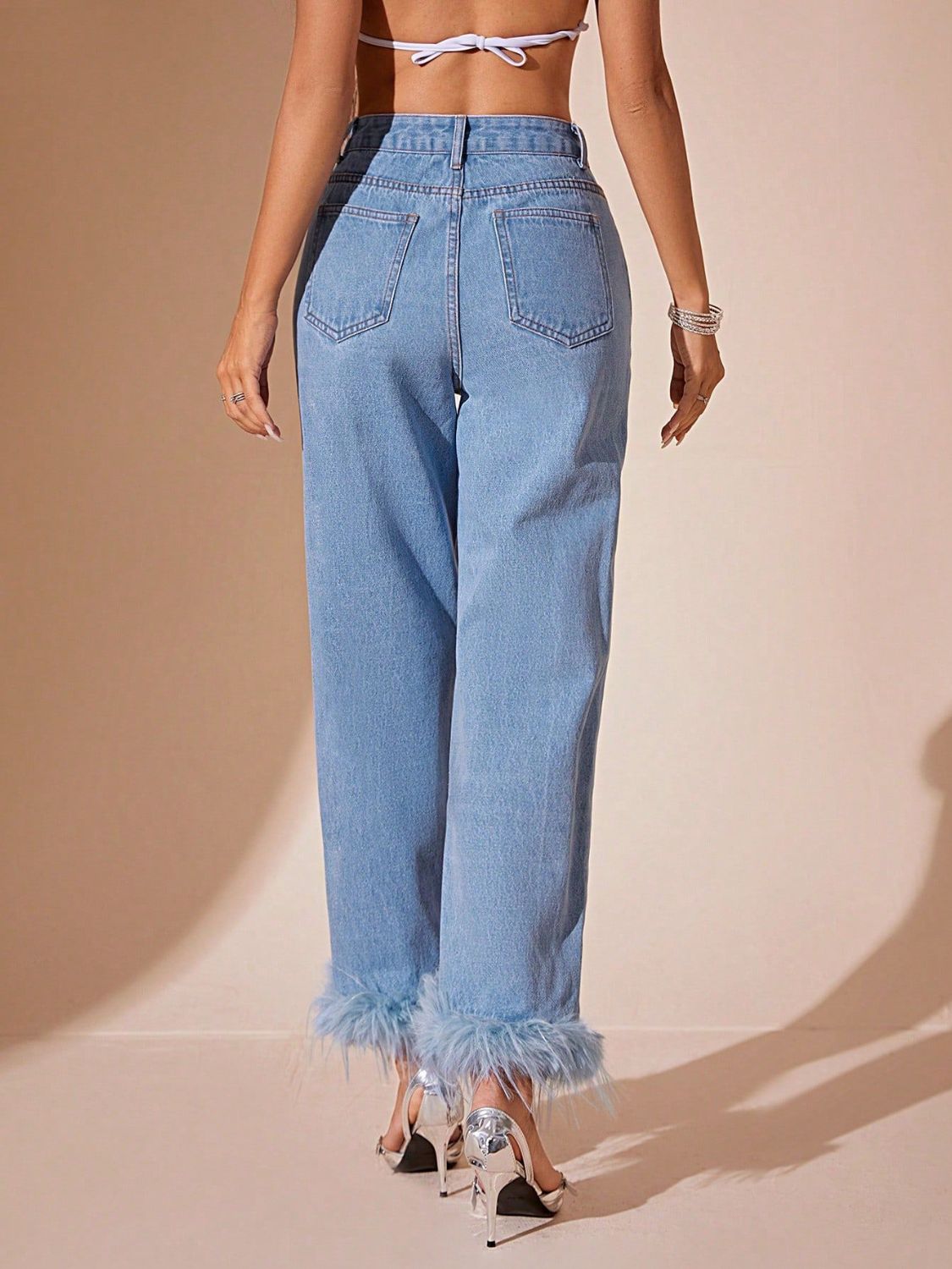 Light wash denim jeans with feather trim cuffs and a high rise fit.