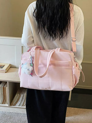Pink quilted tote bag with dual handles, adjustable strap, and a fluffy charm.