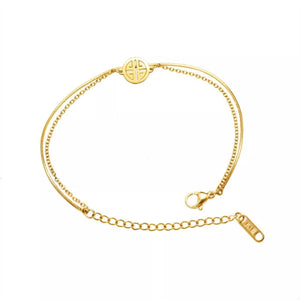 Gold double layered titanium steel bracelet with circular charm and lobster clasp.