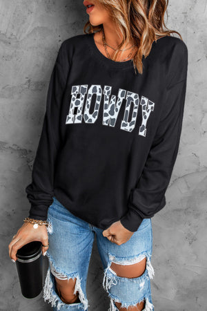 Black crewneck sweatshirt with cow print "Howdy" graphic and long sleeves