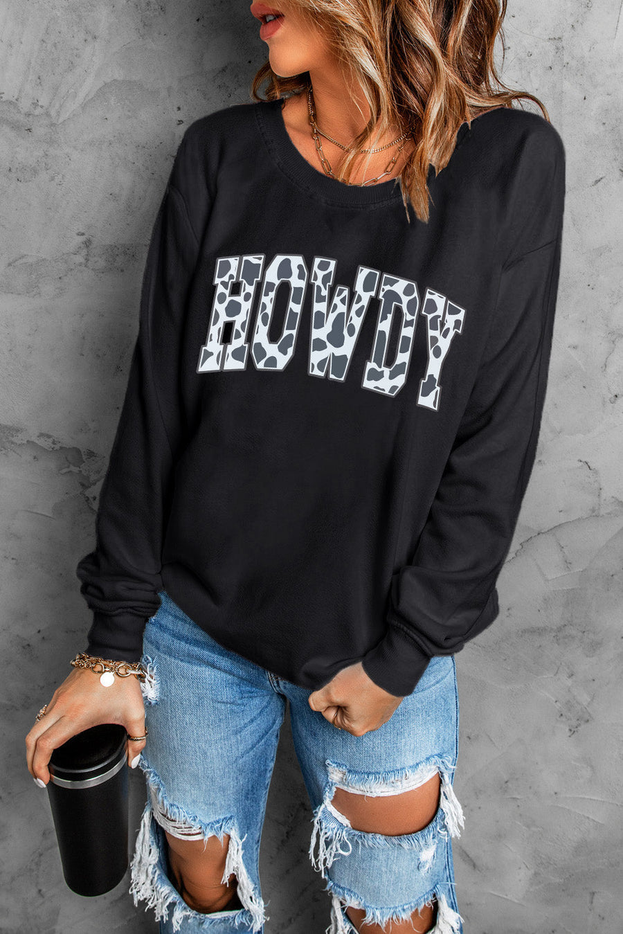 Black crewneck sweatshirt with cow print "Howdy" graphic and long sleeves