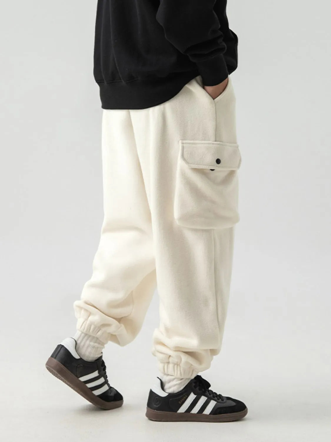 Ivory fleece cargo jogger trousers with elastic cuffs and a single button-flap pocket.
