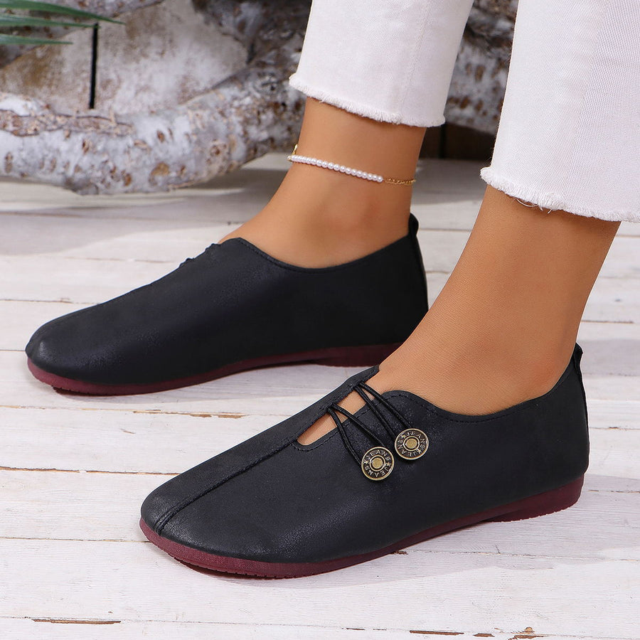 Black round-toe casual flats with decorative buttons and elastic laces.