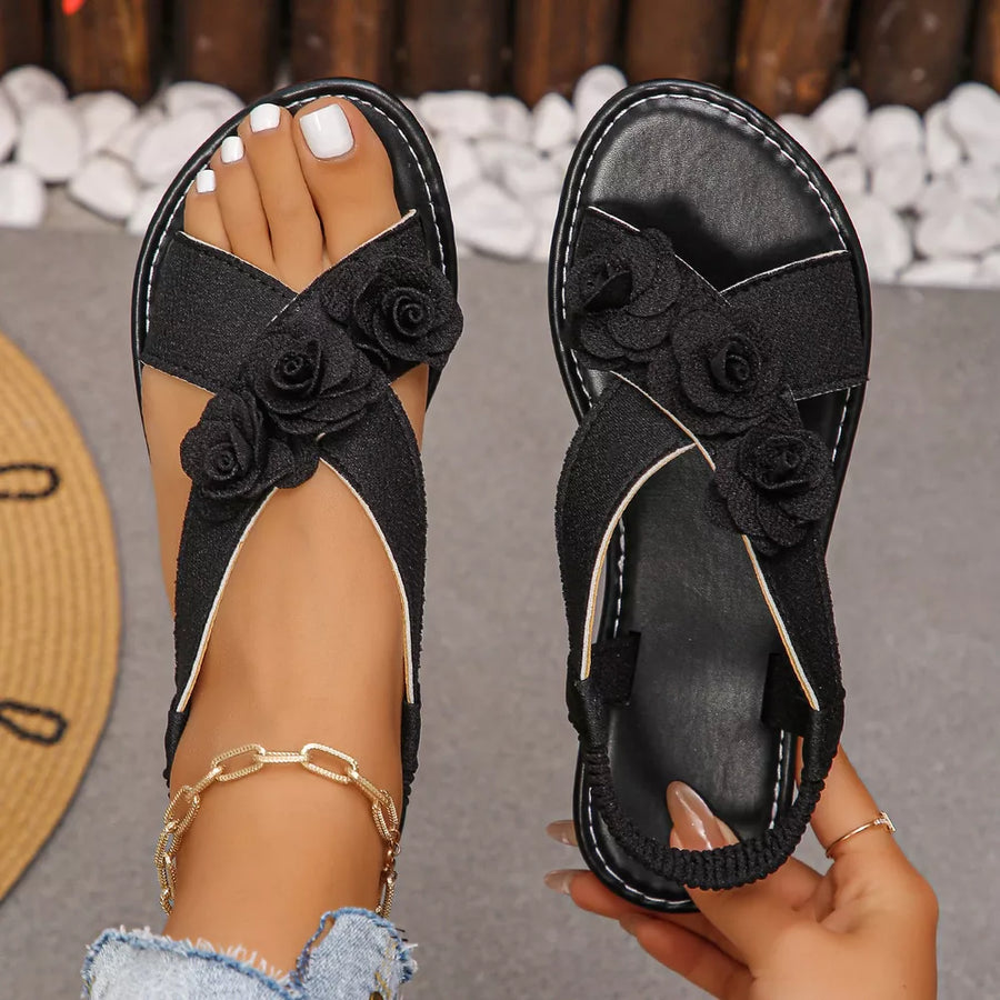 Black slingback sandals with floral embellishments and cross straps.