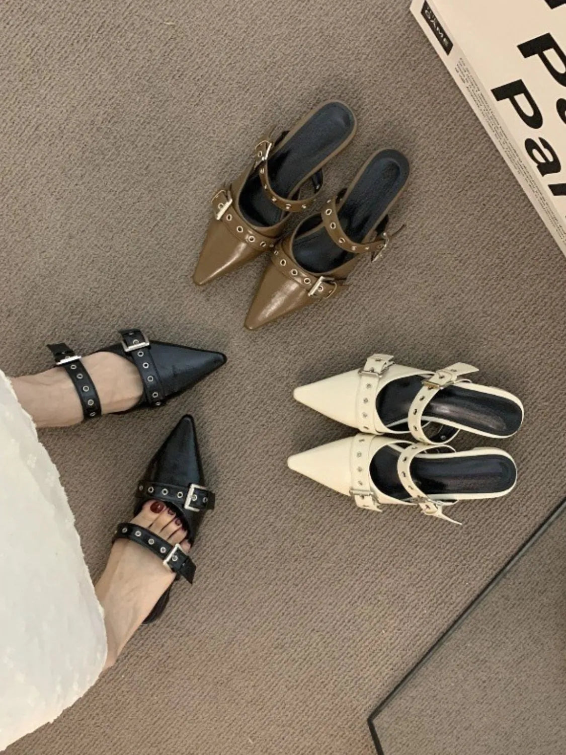 Buckle detail pointed mules in black and beige with stud accents.