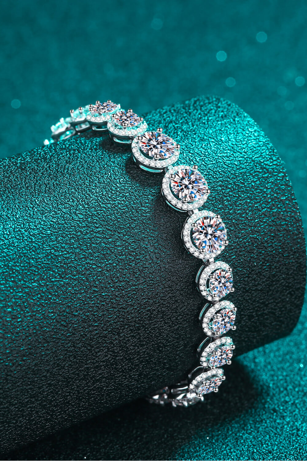 Silver halo moissanite tennis bracelet with round cut stones and halo accents.