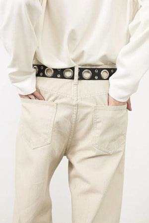 Oversized beige denim jeans with a sculpted leg and a black grommet belt.