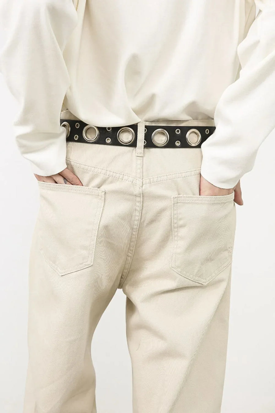 Oversized beige denim jeans with a sculpted leg and a black grommet belt.