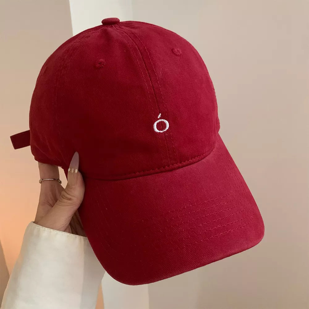 Red cotton baseball cap with curved brim and embroidered 'o' detail
