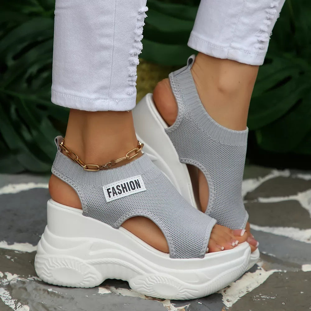 Fashion-forward gray knit open-toe wedge sandals with chunky white sole and gold ankle chain.