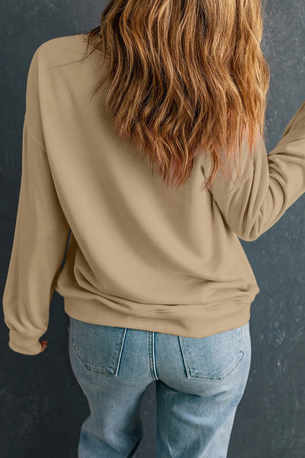 Khaki crewneck sweatshirt with long sleeves and a relaxed fit, styled with jeans.