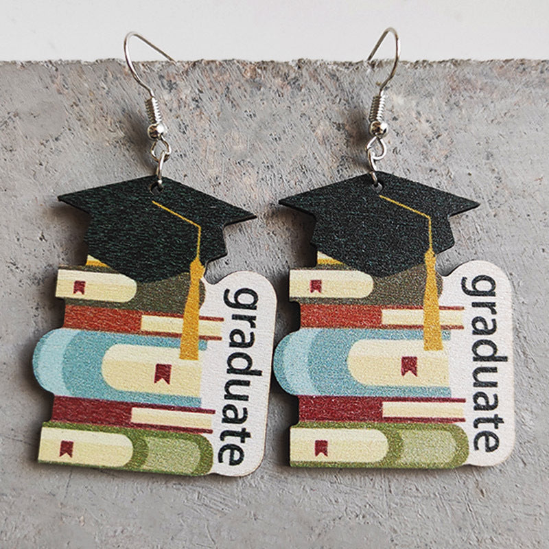 Graduation stacked book drop earrings with black caps and gold tassels.