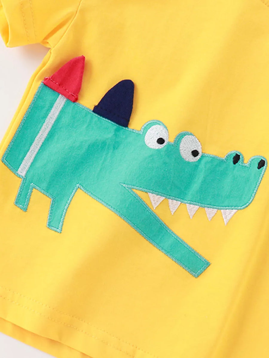 Yellow cotton toddler tee with a green crocodile appliqué and red and blue accents.
