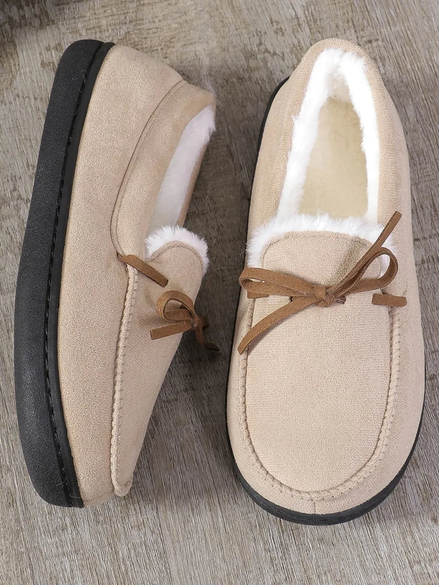 Caramel suede moccasin slippers with white faux fur lining and a decorative bow.