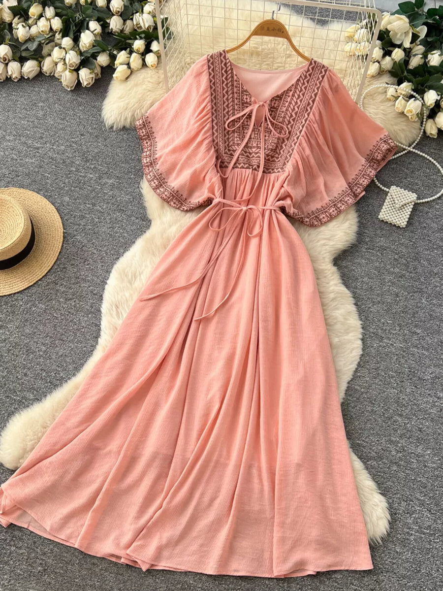 Pink embroidered V-neck maxi dress with flutter sleeves and tie waist.