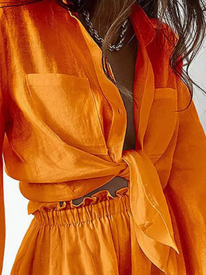 Tangerine two-piece set with a knotted shirt and ruffled waist shorts.