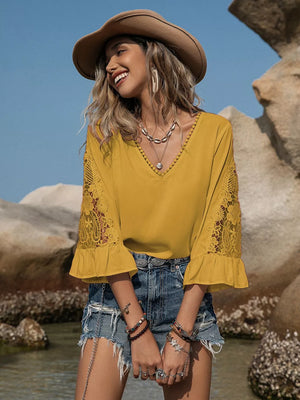 Mustard yellow V-neck blouse with lace bell sleeves and ruffled cuffs.