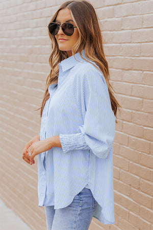 Pastel blue pinstripe blouse with balloon sleeves and ruched cuffs, worn casually.