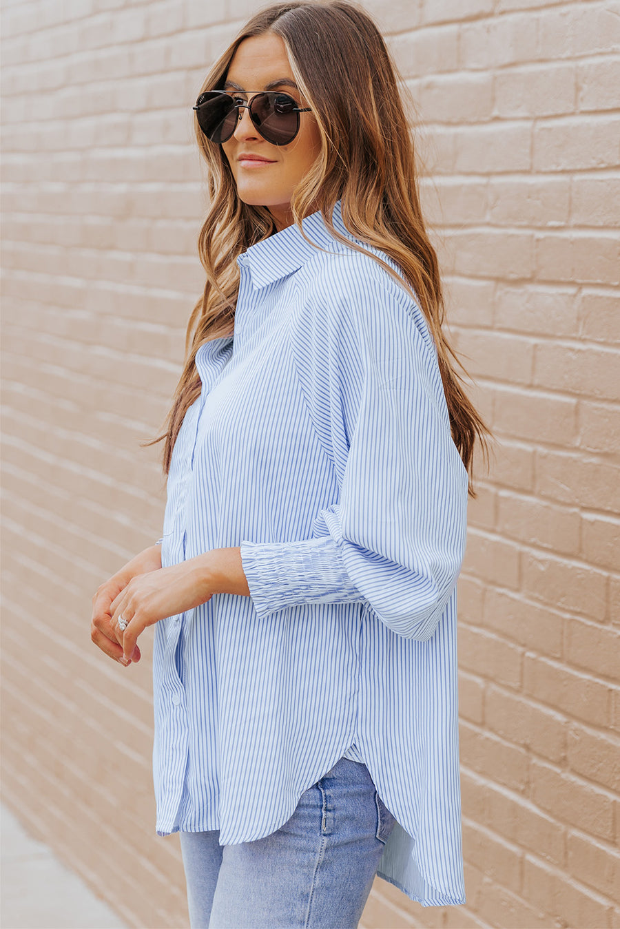 Pastel blue pinstripe blouse with balloon sleeves and ruched cuffs, worn casually.
