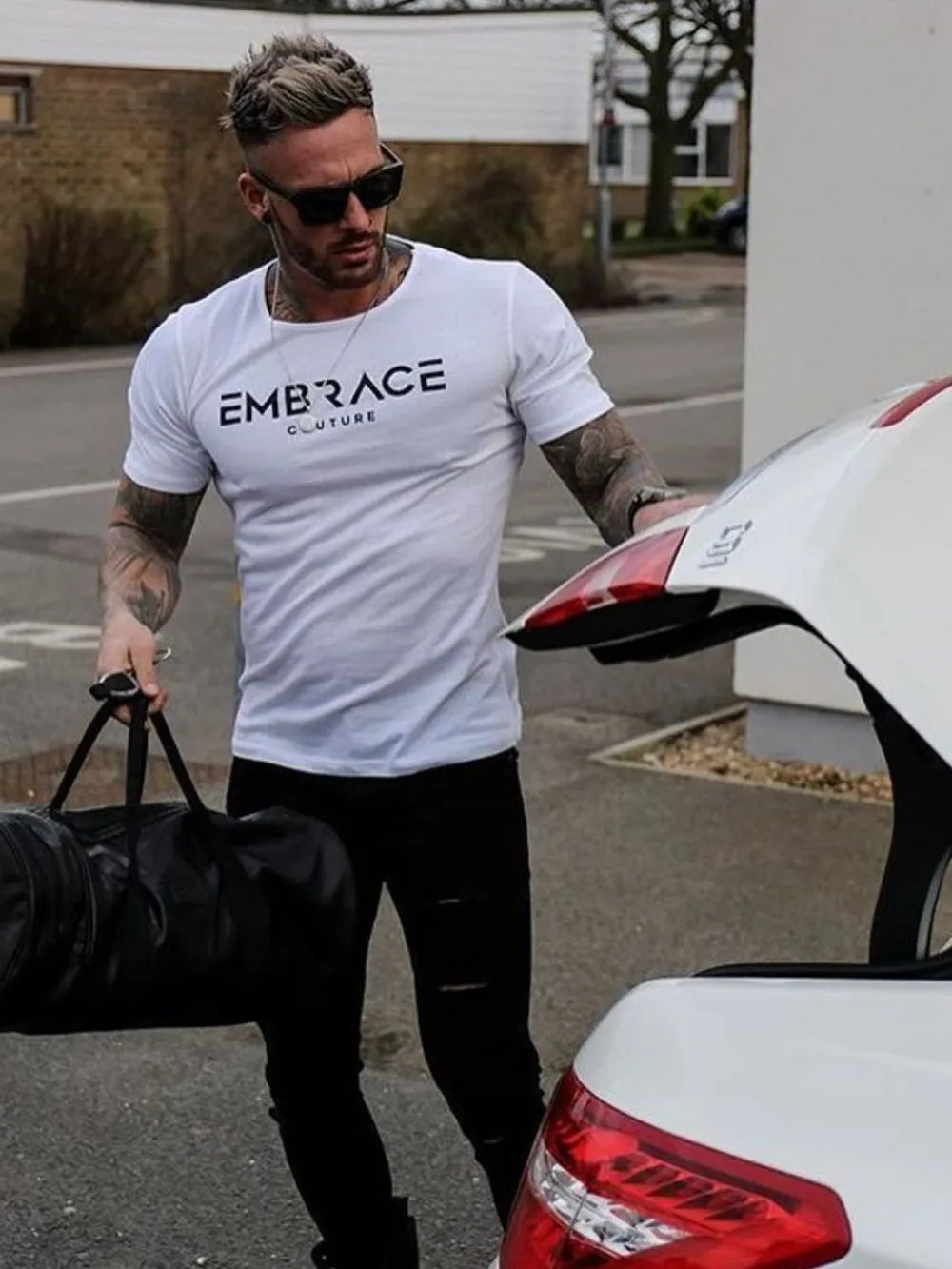White t-shirt with black Embrace Couture logo print, crew neck, short sleeves.