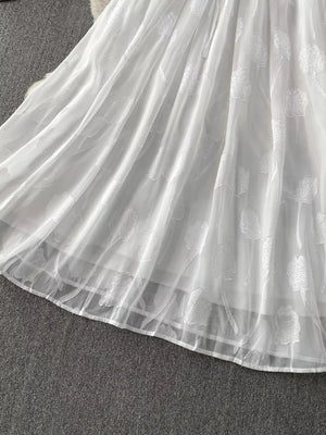 White chiffon maxi dress with floral embroidery and a belted waist.