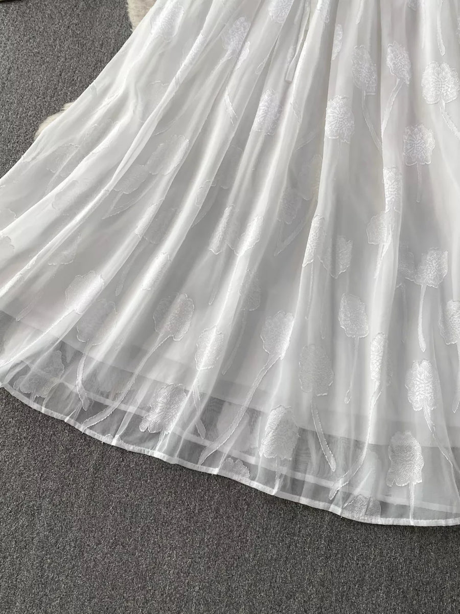White chiffon maxi dress with floral embroidery and a belted waist.