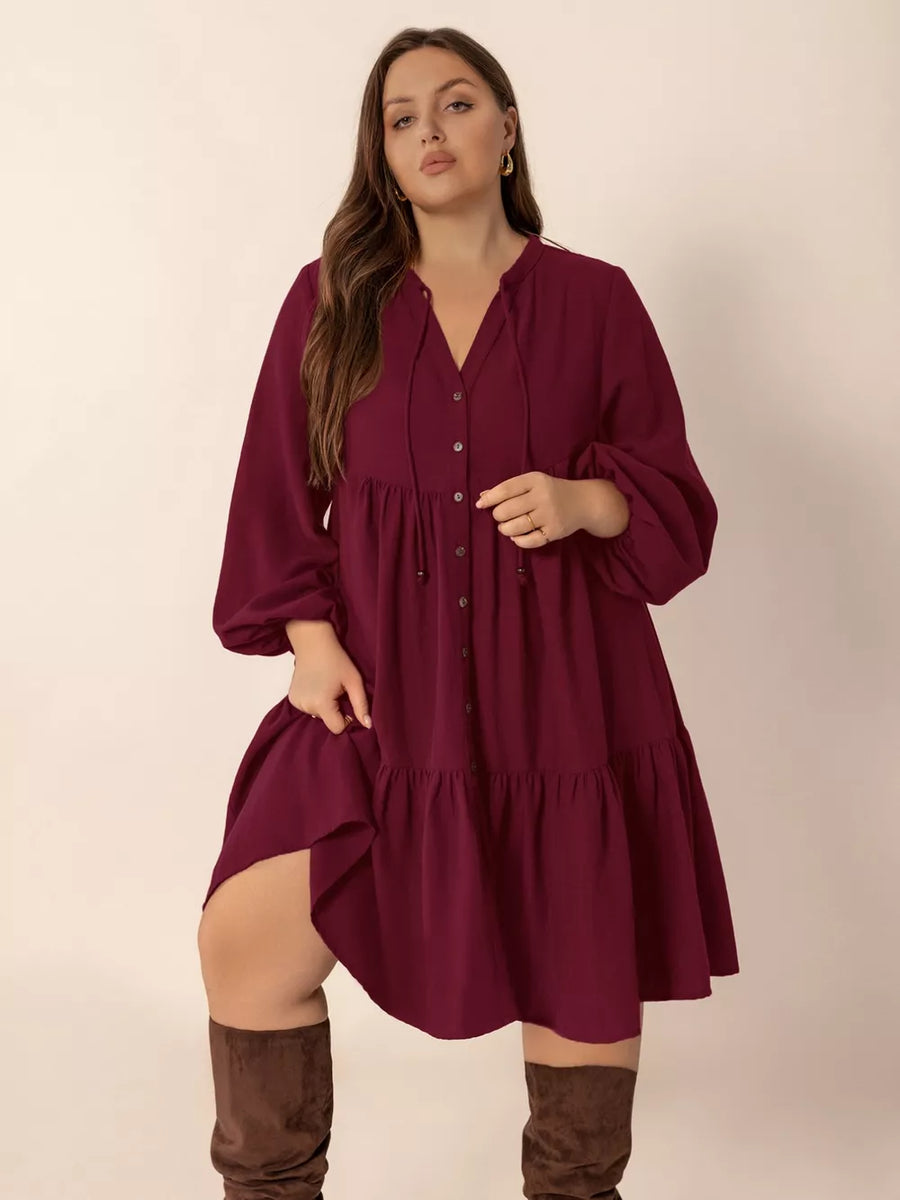 Plus-size burgundy tiered dress with balloon sleeves, V-neck, and button front.