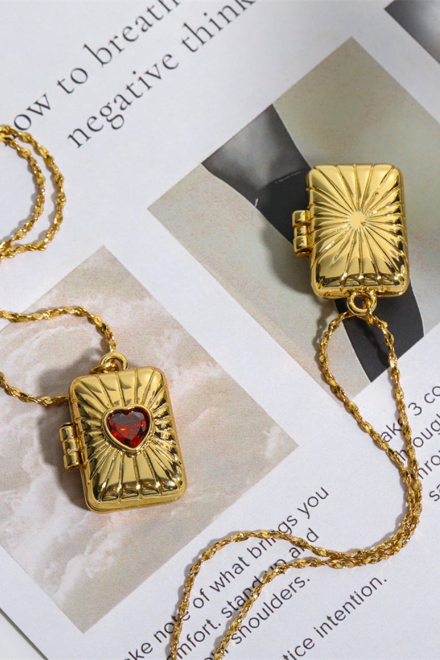 Gold locket pendant necklace with sunburst detail and red heart-shaped stone.