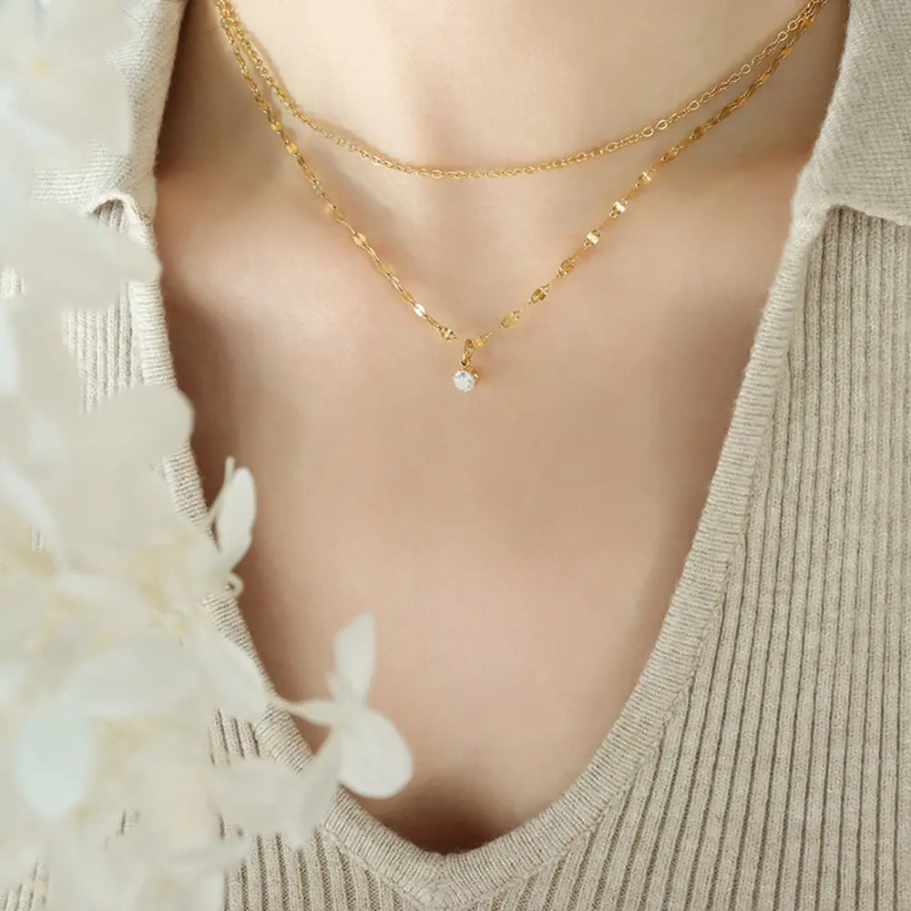 Delicate duo pendant necklace in gold with a single clear stone accent.