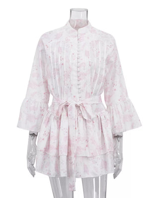 White dress with pink floral print, ruffled bell sleeves, and a tie waist.