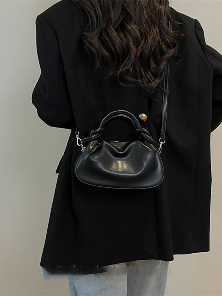 Black ruched crossbody bag with knot handle and adjustable strap.