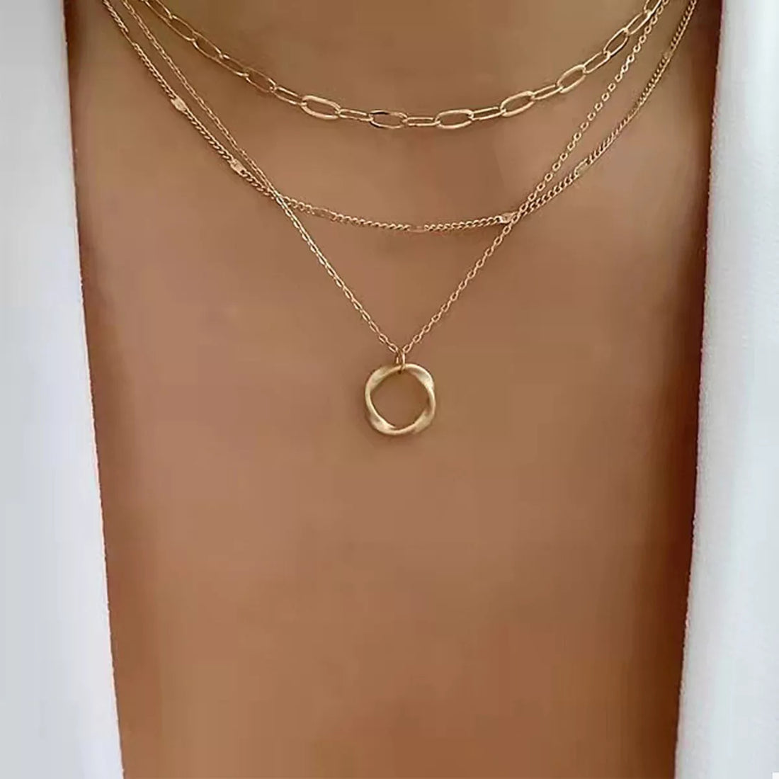 Gold layered necklace with delicate chains and a twisted circle pendant