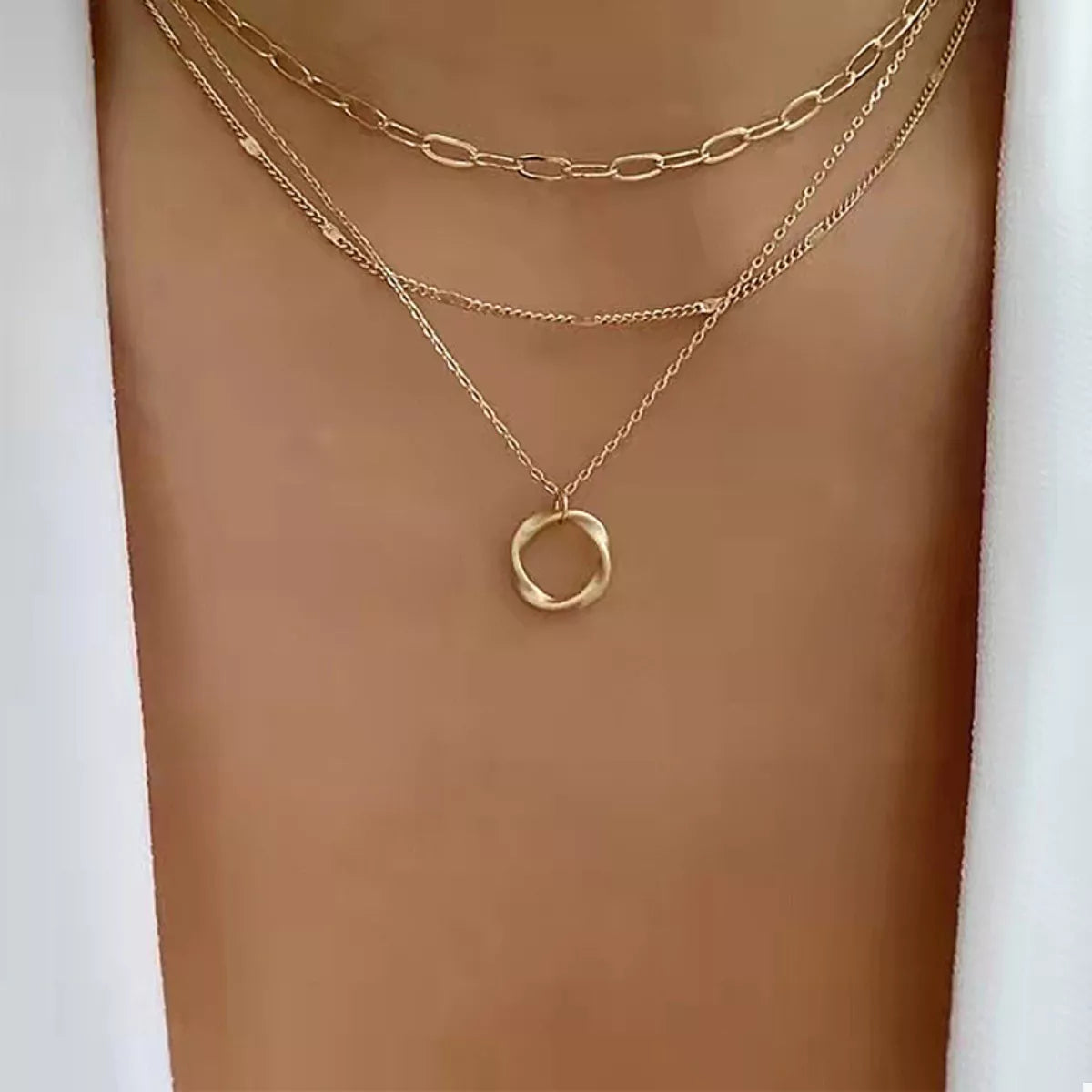 Gold layered necklace with delicate chains and a twisted circle pendant