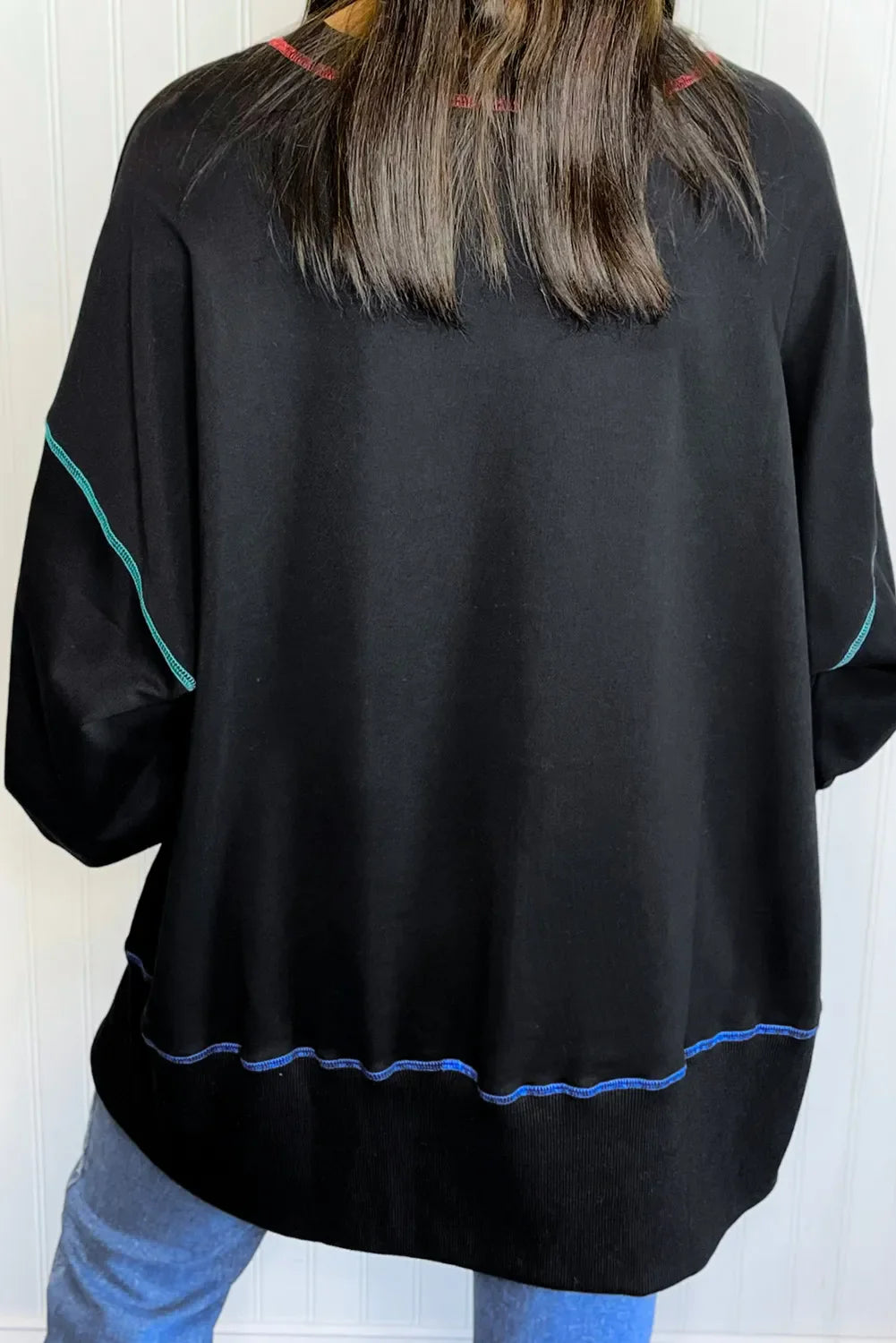 Black sweatshirt with contrast stitching on sleeves and hem, casual fall style.