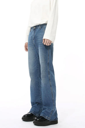 Medium wash denim jeans with pockets and a relaxed fit, styled with a white long-sleeve shirt.