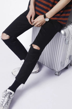 Distressed knee skinny jeans in dark cotton with raw hem detail.